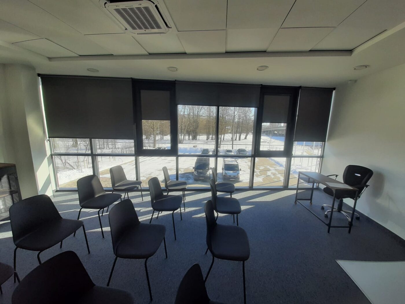 Tumšas screen rullo žalūzijas konferenču zālē — aizsardzība pret sauli bez aptumšošanas Tumšas screen rullo žalūzijas konferenču zālē — aizsardzība pret sauli bez aptumšošanas