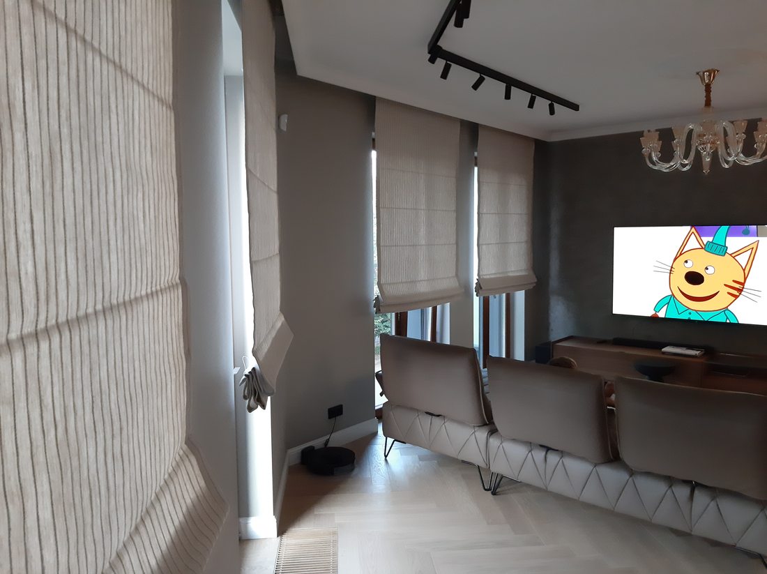 Dubultās romiešu žalūzijas uz viesistabas panorāmas loga